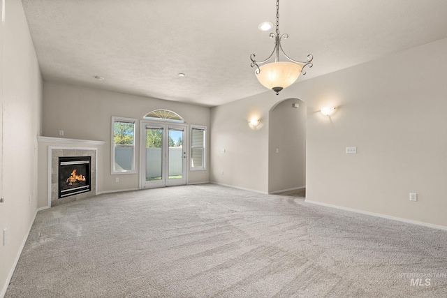 unfurnished living room with carpet, a tile fireplace, and baseboards