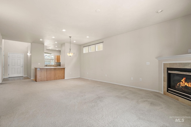 unfurnished living room featuring a tiled fireplace, recessed lighting, light carpet, and baseboards