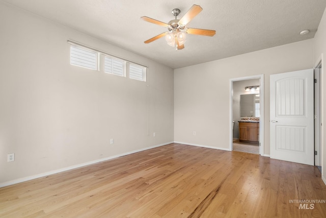 unfurnished room with a ceiling fan, light wood-style flooring, and baseboards