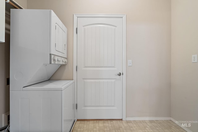 laundry area with stacked washer / dryer, baseboards, and light floors