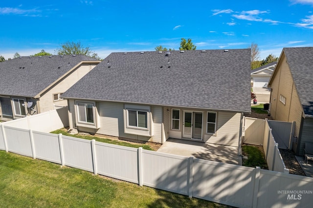 rear view of house with a shingled roof and a patio