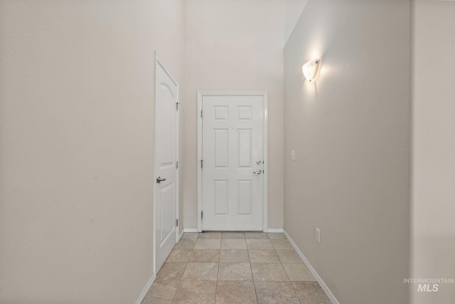 hallway with baseboards and light stone finish floors