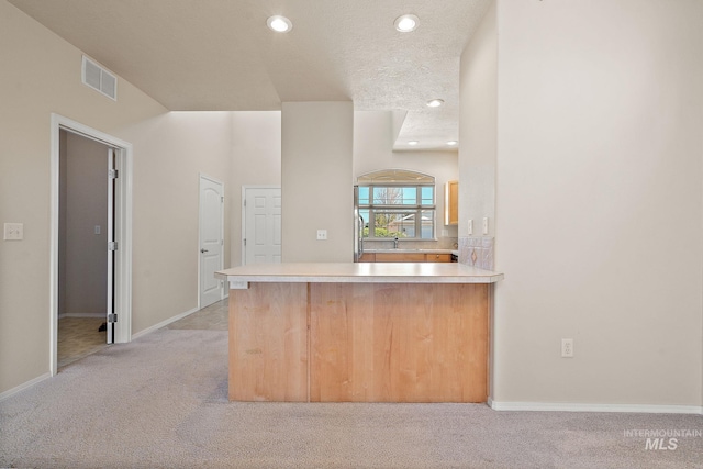 kitchen with light carpet, a peninsula, recessed lighting, a sink, and light countertops