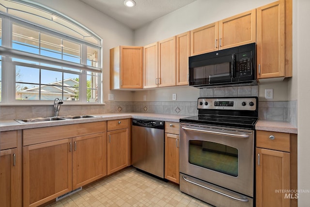 kitchen featuring stainless steel appliances, a sink, light countertops, light floors, and recessed lighting