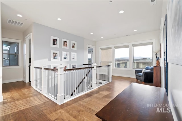 hallway with wood finished floors, recessed lighting, an upstairs landing, and visible vents