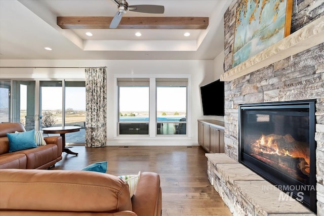 living room featuring a fireplace, beam ceiling, wood finished floors, and a wealth of natural light