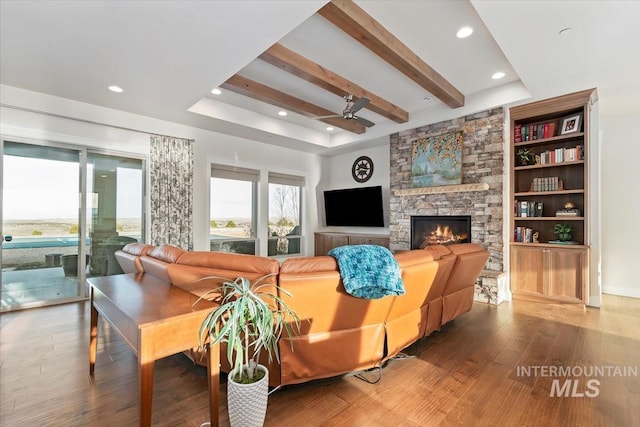 living area with wood finished floors, a ceiling fan, a fireplace, recessed lighting, and beamed ceiling