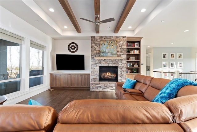 living area with recessed lighting, beamed ceiling, a stone fireplace, and dark wood-style flooring