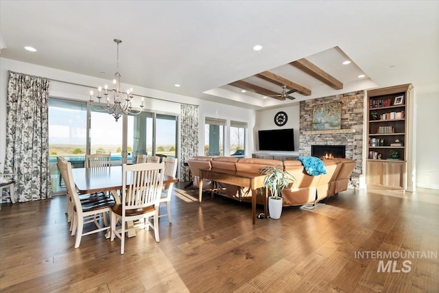 dining area featuring beamed ceiling, ceiling fan with notable chandelier, wood finished floors, recessed lighting, and a fireplace