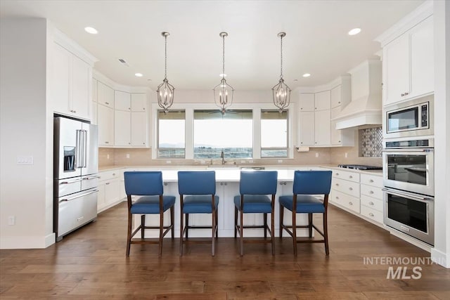 kitchen featuring stainless steel appliances, custom exhaust hood, a center island, and light countertops