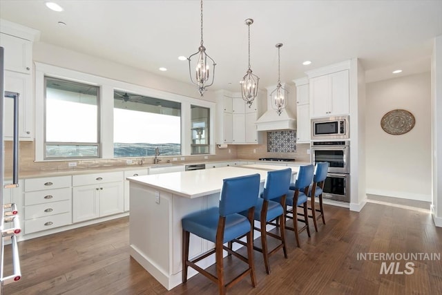 kitchen with a wealth of natural light, a kitchen island, appliances with stainless steel finishes, and a sink