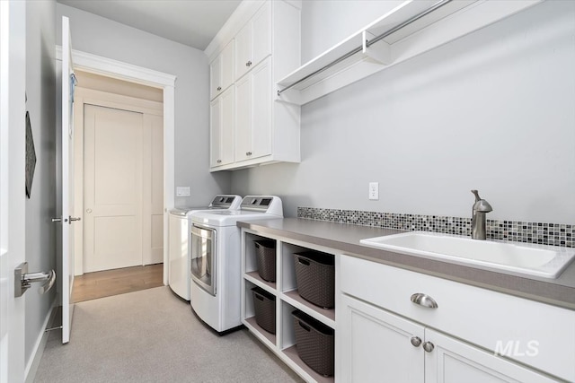 laundry area with washer and clothes dryer, cabinet space, and a sink