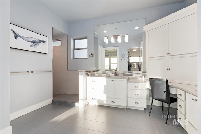 bathroom featuring baseboards, walk in shower, decorative backsplash, tile patterned floors, and vanity