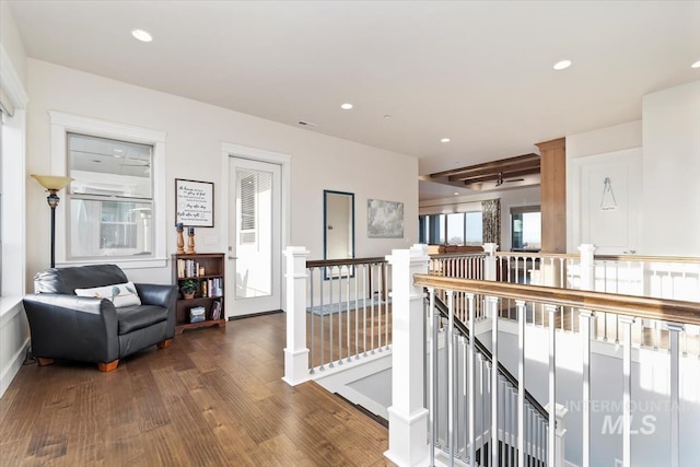 hall featuring wood finished floors, recessed lighting, and an upstairs landing