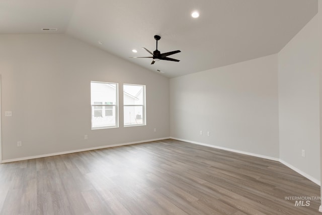 empty room with a ceiling fan, visible vents, wood finished floors, and lofted ceiling