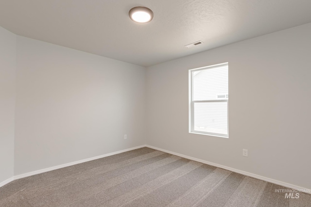unfurnished room with baseboards, carpet, and visible vents