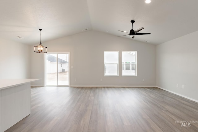 spare room featuring baseboards, vaulted ceiling, wood finished floors, and ceiling fan with notable chandelier