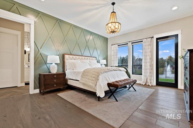 bedroom with access to exterior, an inviting chandelier, and dark wood-type flooring