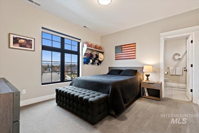 bedroom with light colored carpet and ensuite bath