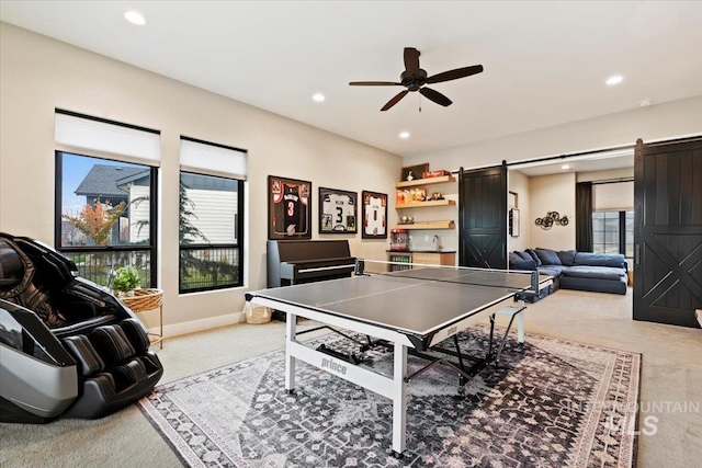 rec room featuring a barn door, ceiling fan, and carpet floors