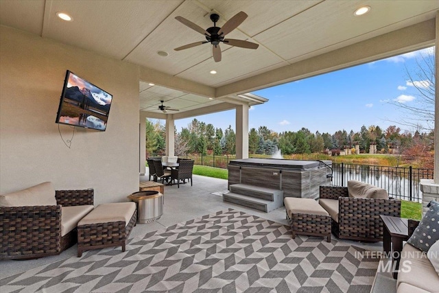 view of patio / terrace featuring ceiling fan, a water view, and an outdoor living space