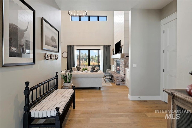 interior space featuring a notable chandelier, light hardwood / wood-style floors, and a stone fireplace