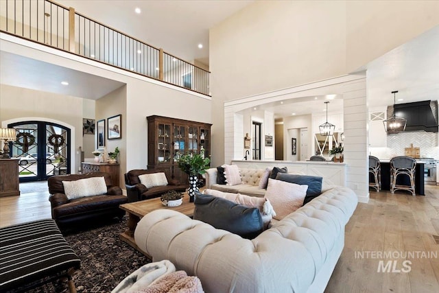 living room featuring light hardwood / wood-style flooring, a towering ceiling, and french doors