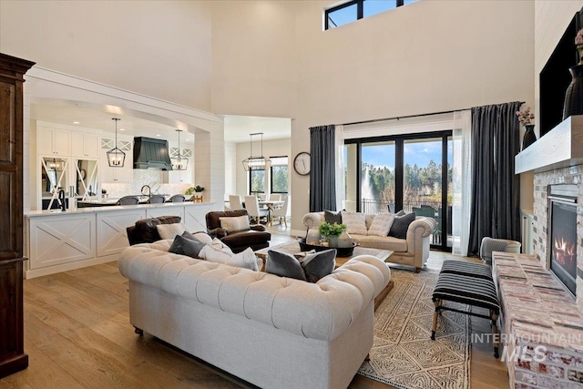 living room with a fireplace, a towering ceiling, and light hardwood / wood-style floors