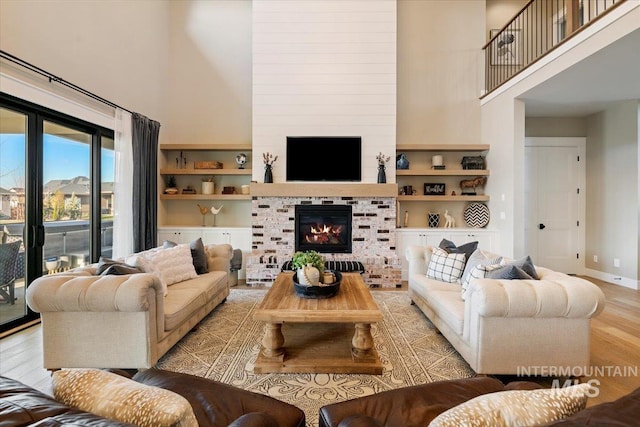 living room with a large fireplace, a high ceiling, and light hardwood / wood-style flooring