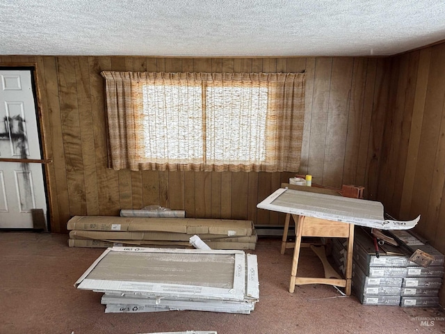 unfurnished dining area with carpet floors, a baseboard radiator, wood walls, and a textured ceiling