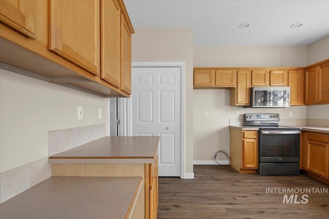 kitchen with a textured ceiling, dark hardwood / wood-style flooring, and stainless steel appliances