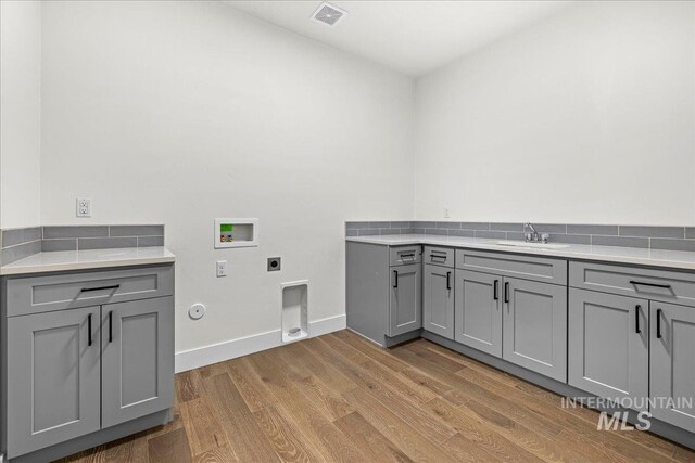 laundry area with gas dryer hookup, hookup for a washing machine, light hardwood / wood-style flooring, electric dryer hookup, and sink