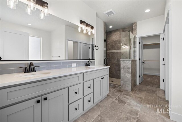 bathroom with oversized vanity, backsplash, a shower with shower door, tile flooring, and dual sinks