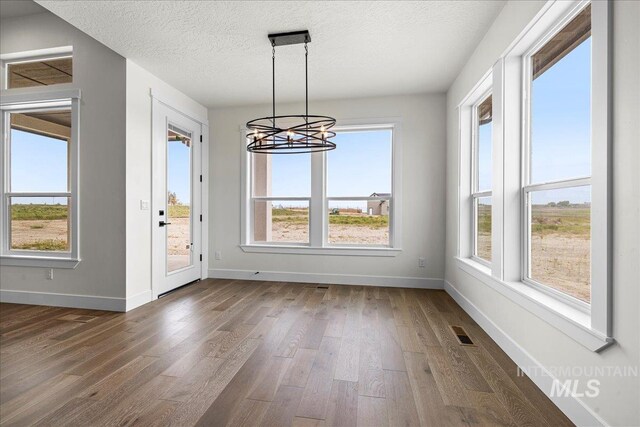 unfurnished dining area with plenty of natural light, dark hardwood / wood-style flooring, and a textured ceiling