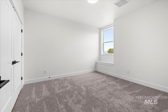 carpeted empty room featuring a textured ceiling