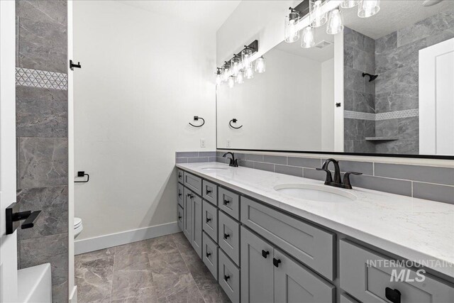 bathroom with vanity with extensive cabinet space, tile walls, double sink, tile flooring, and toilet