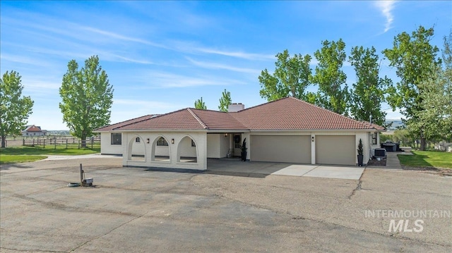 mediterranean / spanish home with a garage, driveway, a tile roof, a chimney, and fence