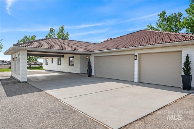 view of front facade featuring a garage, a tiled roof, and concrete driveway