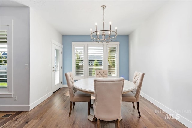 dining area featuring an inviting chandelier, visible vents, baseboards, and wood finished floors