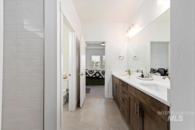 bathroom with connected bathroom, a sink, toilet, and double vanity