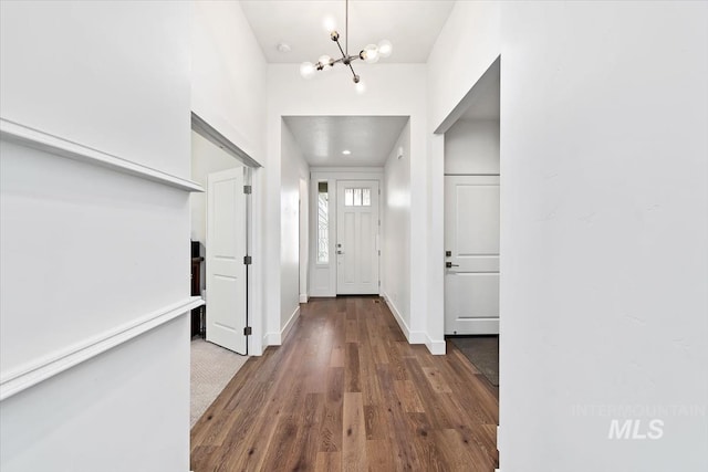 entrance foyer featuring baseboards, wood finished floors, and an inviting chandelier