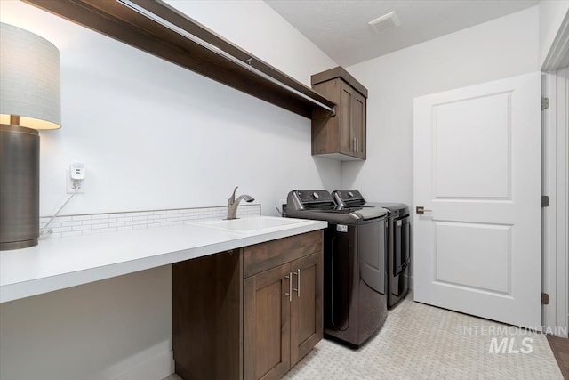 washroom with visible vents, washing machine and dryer, a sink, and cabinet space