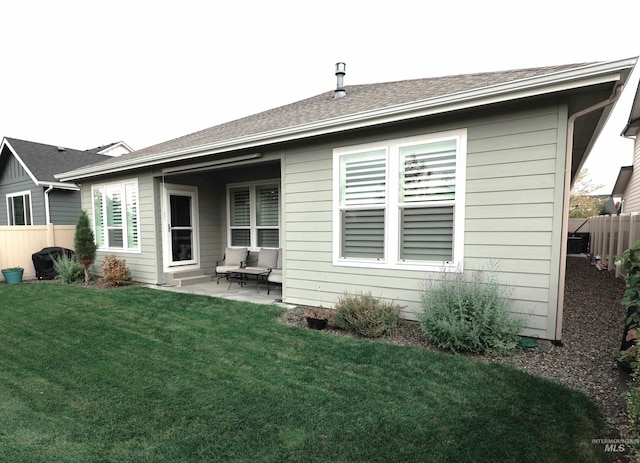 back of house featuring a yard, roof with shingles, a patio area, and fence