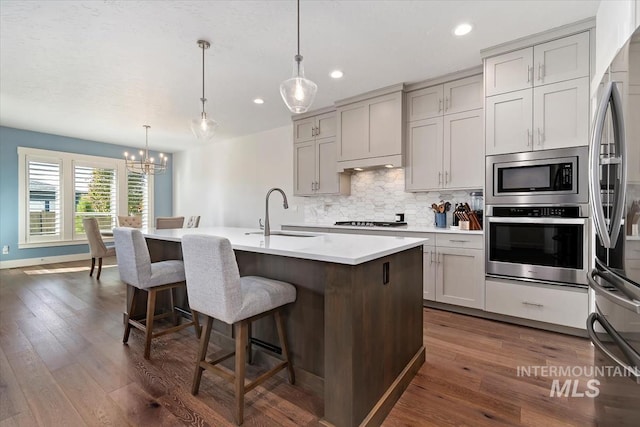 kitchen featuring dark wood-style flooring, a sink, appliances with stainless steel finishes, gray cabinets, and tasteful backsplash