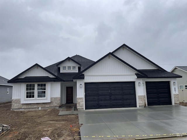 view of front facade with a garage, concrete driveway, roof with shingles, and stone siding