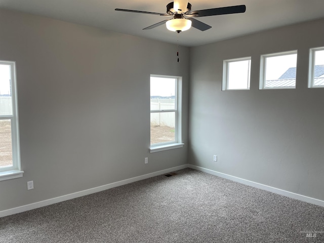 carpeted empty room featuring baseboards and a ceiling fan