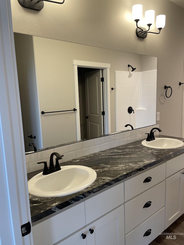 bathroom with a sink, a tile shower, and double vanity