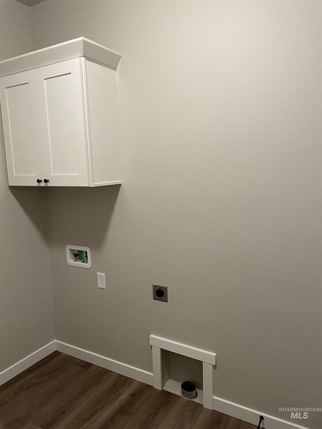 washroom featuring electric dryer hookup, cabinet space, baseboards, and dark wood-style floors
