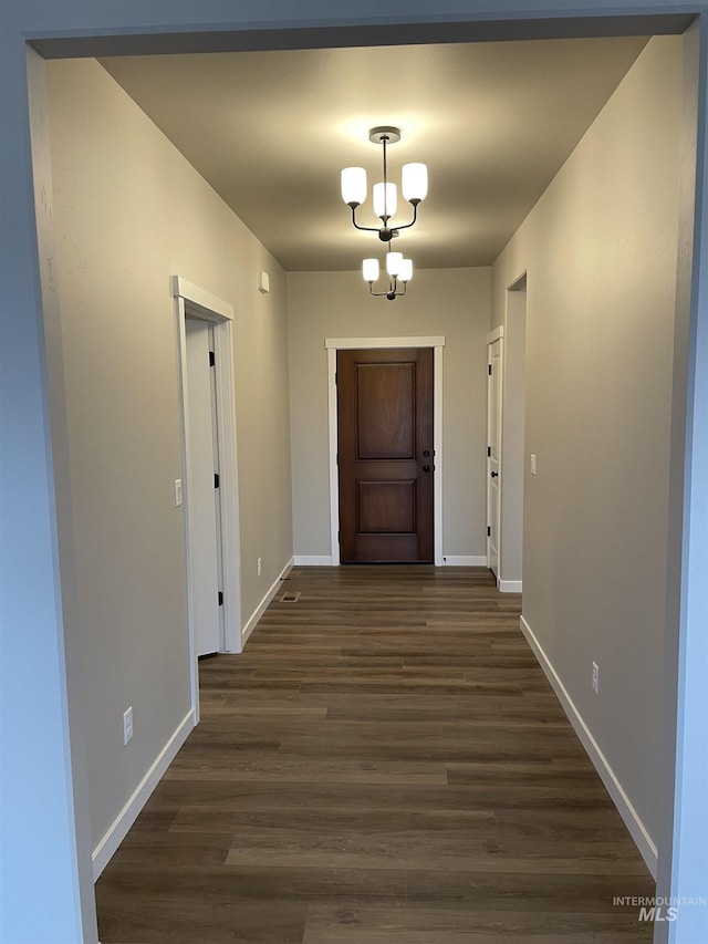 doorway with baseboards, dark wood-style flooring, and an inviting chandelier