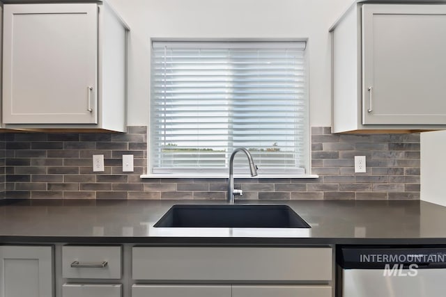 kitchen with white cabinetry, stainless steel dishwasher, sink, and backsplash